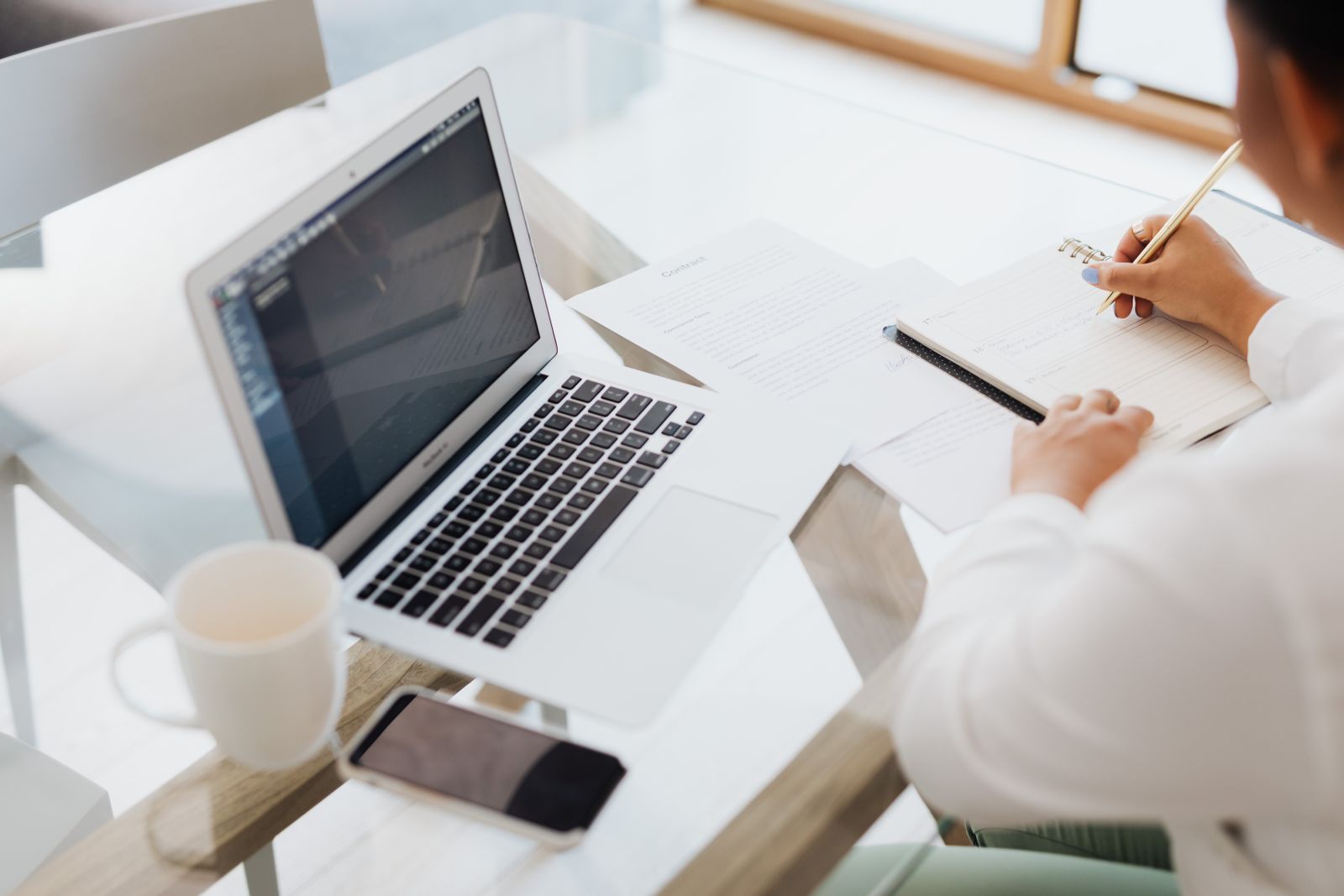 Person planning a website layout at a desk with a notebook and coffee