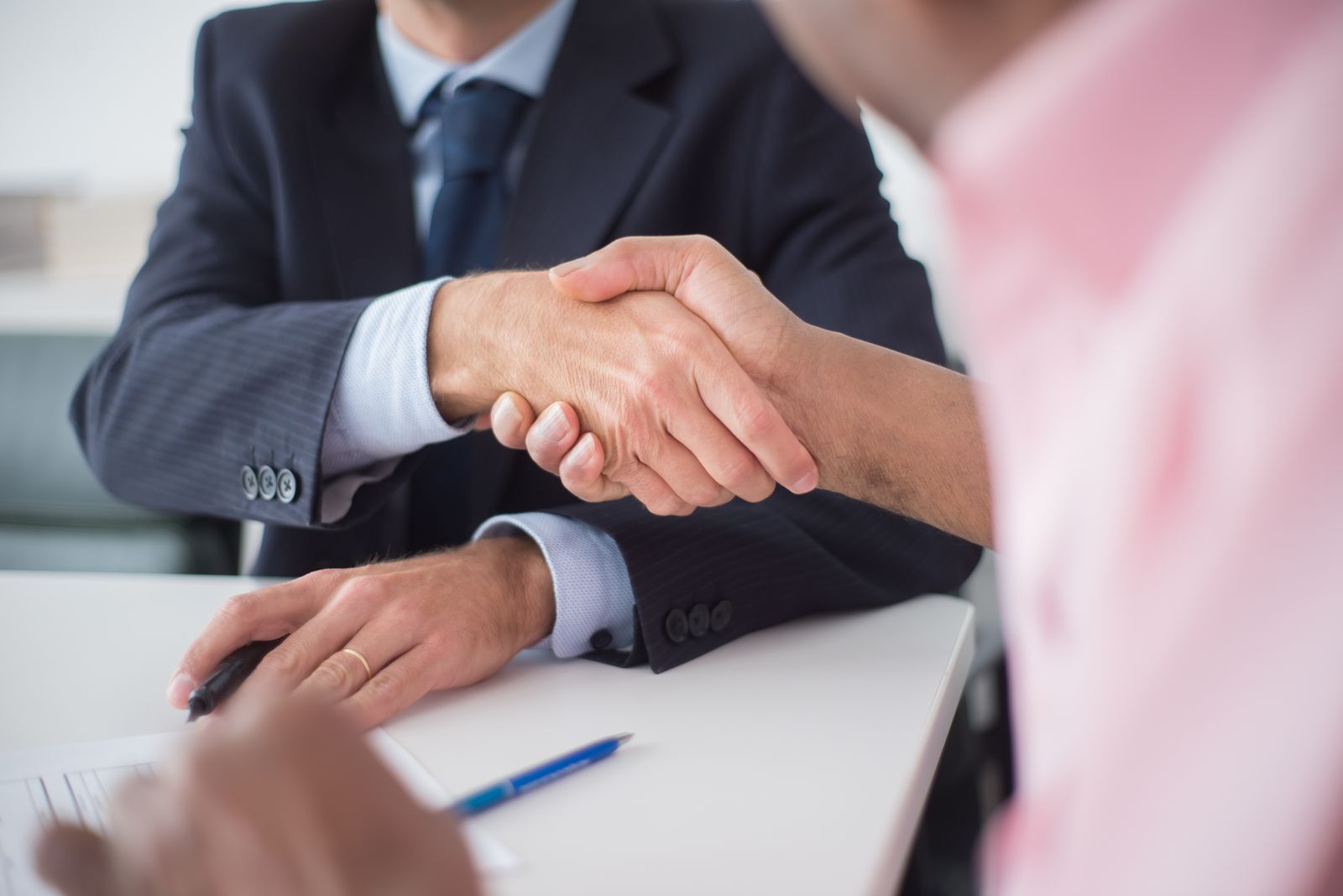 Two people shaking hands across a table after agreeing a job